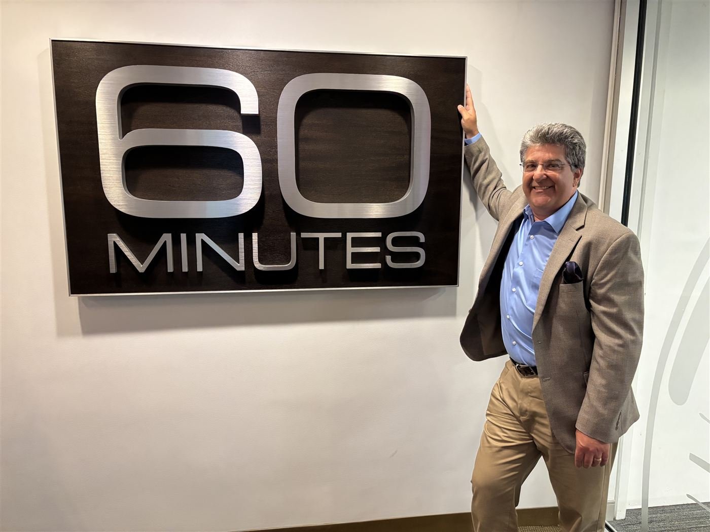 Guy Campanile standing beside the 60 Minutes wall sign